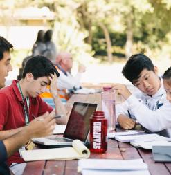 After class, students work together at a picnic table.
